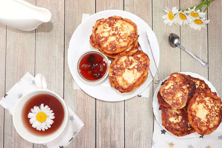 Delicious Russian pancakes with cherry jam and chamomile herbal tea on a bright light table. Healthy...