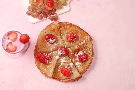 Delicious Russian pancakes with strawberries and yogurt on a bright light table. Healthy breakfast with ingredients, natural products, traditional national cuisine, selective focus, rustic styleの写真素材