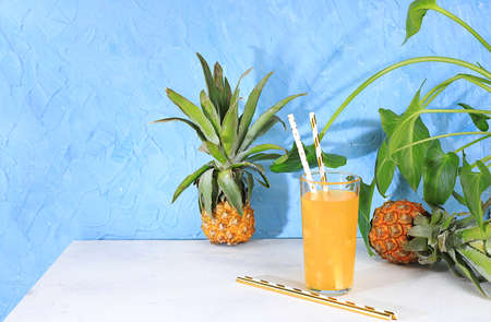 Fruit juice and ingredients, summer pineapple drink and mini pineapple on bright table with long...