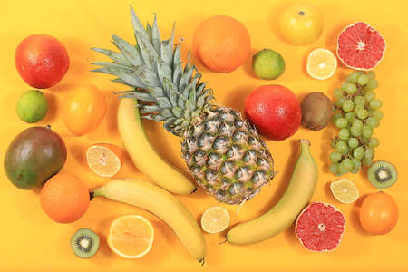 Detox diet and weight loss concept. summer tropical fruits and vegetables on yellow table, top view, healthy and natural food, source of vitamin C, banner for shop, selective focus, place for textの写真素材
