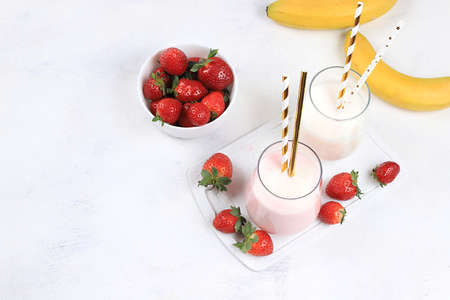Strawberry and banana smoothies with berries and banana on a bright table. Useful breakfast made with ingredients. Healthy and natural food concept, lifestyle, selective focus,の写真素材
