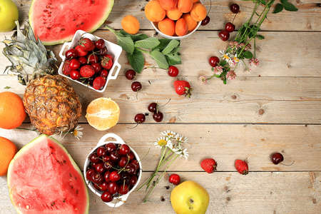 Summer berries and fruits on wooden background, healthy natural food concept, breakfast with ingredients, top view, advertisement for a store, business card for a cafe, invitation with place for text, selective focusの写真素材