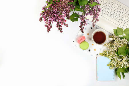 Modern woman's desktop, home office, a cup of flower tea and cookies on a light table with lilac flowers. Healthy breakfast with ingredients, healthy lifestyle concept, flat layの写真素材