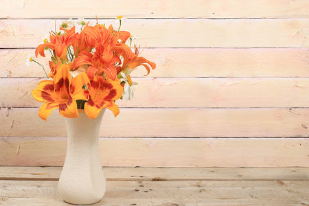 Lilies and daisies in a vase on an old wooden table, Abstract flower arrangement, background, minimal holiday concept, rustic style. Mother's day card, happy birthday, wedding, place for text, selective focusの写真素材