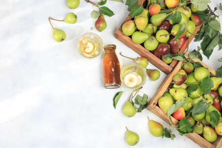 Apple and pear mulled wine with honey, cider, juice or fruit drink in a glass on a sunny table with fresh pears in boxes. The concept of diet and weight loss, harvesting in the village. Healthy eating, body detoxification, selective focusの写真素材