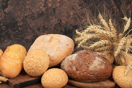 Freshly baked homemade sourdough bread with crispy crust and ears of rye and wheat on an old wooden...