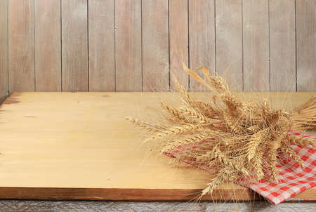 Empty wooden table with sheaf of wheat on old background with place for text, rustic style, bakery and harvest concept, mock up for design and showcase for product showcase,の写真素材