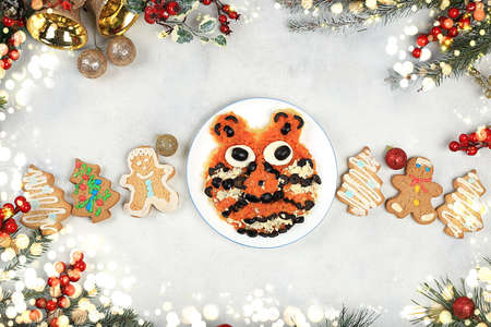 Christmas new year dishes, traditional festive tiger cub salad, symbol of the year made of carrots, olives, cheese for vegan food, fir branches and cones and decorations, food design idea, place for recipe, flat lay,の写真素材