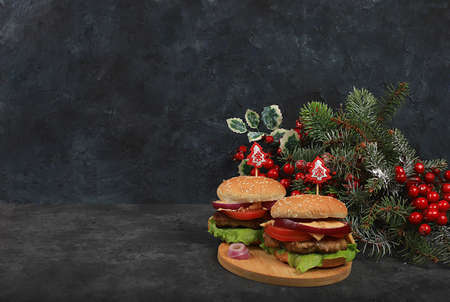 Two Christmas burgers on a festive table with a live tree and decorations, new year food.Advertising banner for a cafe or shopの写真素材