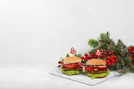 Two Christmas burgers on a festive table with a live tree and decorations, new year food.Advertising banner for a cafe or shop,の写真素材