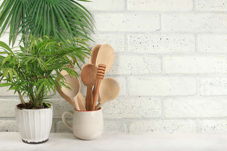 Empty table with wooden appliances, utensils and palm leaves. Kitchen interior, mockup for design...