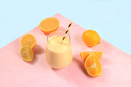 Modern still life with citrus, orange smoothie and ingredients on pink background with shadows, minimal detox diet concept, summer vitamin drinks, selective focus, space for textの写真素材