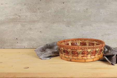 Empty basket with tablecloth on wooden table on old wall background, rustic style, eco concept,...