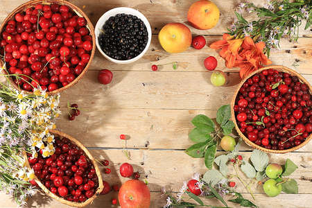 Summer cherry berries and fruits on a wooden background with lilies and daisies, wild flowers,...
