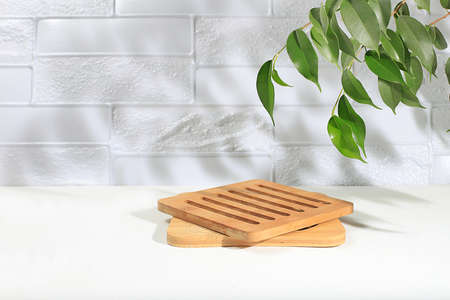 Minimal abstract background for the presentation of cosmetic products. Premium empty podium with shadows of tropical leaves on light wall and wooden stand, template for design, pedestal podium, selective focusの写真素材