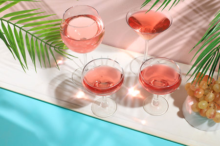 Modern still life with white wine, alcoholic margarita cocktail and grapes on a pastel background with long hard shadows, minimal concept for a bar, cafe, advertising banner, selective focusの写真素材