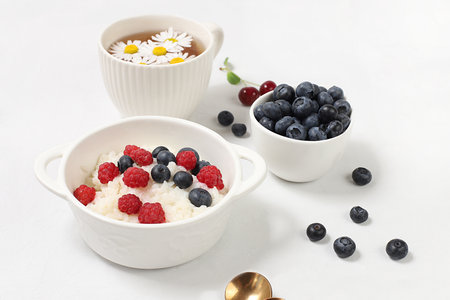 Healthy breakfast with ingredients, milk rice porridge with fresh blueberries, cherries and...