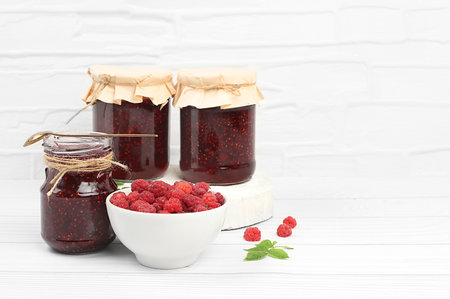 Village harvest, jars of raspberry jam on light wooden background with leaves, shop banner and...