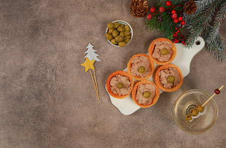 Christmas and New Year's dishes, a set of snacks and refreshing drinks for the holiday table. Plate with tartlets of pate, cheese and olives on a concrete table, selective focusの写真素材