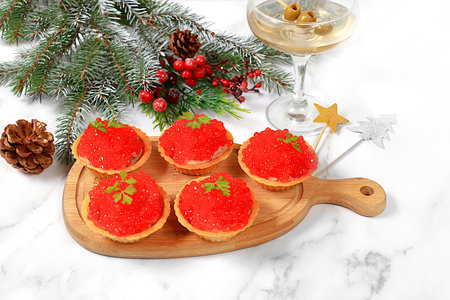 Christmas and New Year's dishes, a set of snacks and refreshing drinks for the holiday table. Plate with pate tartlets and red salmon caviar on a concrete table, selective focusの写真素材