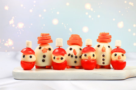 Christmas New Year's dishes, funny figures of snowmen made from eggs, mozzarella cheese, tomatoes and carrots. Idea for preparing holiday dishes, New Year's Eve concept, selective focusの写真素材