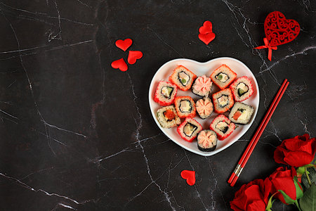 Valentine's Day food, Heart of fresh sushi rolls with roses, traditional Japanese cuisine, banner for advertising or invitation bar, menu, place for text, top view, selective focusの写真素材