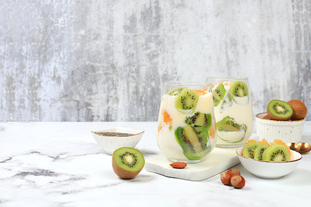 Fruit yogurt, kiwi, muesli, almonds, tangerines and chia seeds for weight loss. Healthy breakfast with ingredients, kitchen background. Concept of natural nutrition and detox diet, lifestyle, selective focus,の写真素材