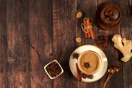Cup of coffee with milk, ginger, anise and cinnamon on an old wooden table. Traditional Indian drink with spices, cafe concept, advertising for restaurant and menu. Selective focusの写真素材