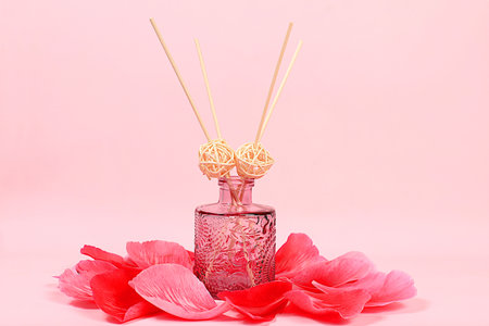 Diffuser bottle with rose extracts and peony petals on elegant background, concept of natural organic cosmetics and aromatherapy, spa and store advertising, minimal composition, selective focus.の写真素材