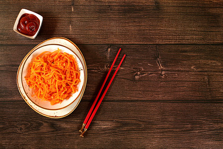 Korean kimchi side dish for barbecue dinner, carrot with sauce and hot pepper, set of fermented foods good for gut health. Carrot, cabbage, garlic, parsley and juice on wooden background, healthy breakfast with ingredientsの写真素材