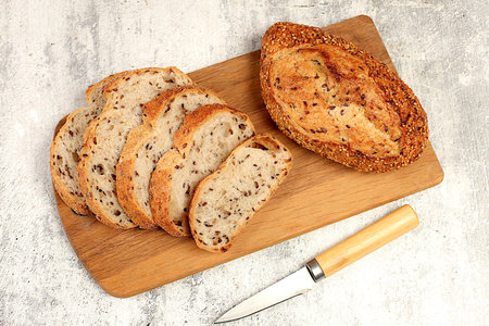 Freshly baked whole grain homemade sourdough bread with crispy crust, sliced on concrete table,...