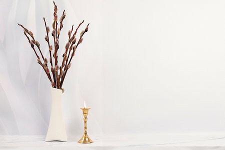 Delicate pussy willow flowers in vase and candle on gray background, abstract spring floral arrangement. Easter card and still life, minimal holiday concept, home interior, selective focusの写真素材
