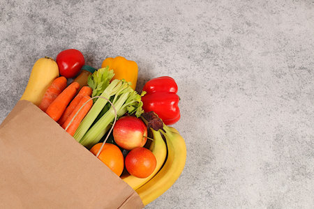 Paper eco bag with healthy vegan products for weight loss. Lemons, oranges, apples, bananas, bell peppers and natural juice in a craft bag, food delivery concept, store advertisingの写真素材