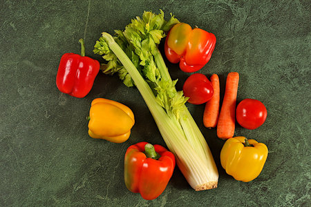 Sweet bell peppers, tomatoes, celery and carrots on a concrete table. Modern still life of various ripe vegetables for healthy vegetarian food and detox diet, harvesting. Advertisement of a store and marketの写真素材