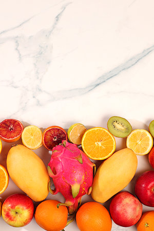 Dragon fruit, pitaya, mango, kiwi, avocado, apples, citrus on a sunny table with space for text....