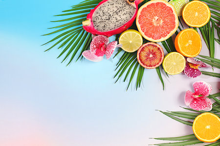 Dragon fruit, pitaya, oranges, lemons, orchid flowers on palm leaves, tropical background with palm trees and exotic fruits, beautiful template for your design, bright sunny banner, summer in a snapshot.の写真素材