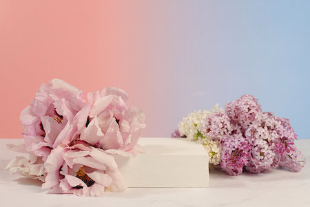 Empty podium with spring mountain peony flowers and lilac flowers.Abstract floral arrangement with peonies, banner. Creative template for your design.Minimal modern aesthetics, elegant beauty concept,の写真素材