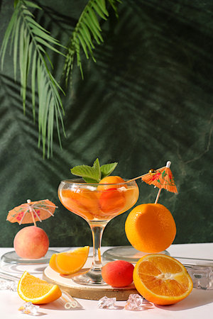 Modern still life with fruits. Alcoholic cocktail or punch, berries peach, apricot and mint on elegant background, minimalist concept for bar and holiday party, cafe, advertising banner,の写真素材