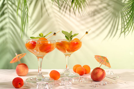 Modern still life with alcoholic cocktail or punch, peach, apricot and mint berries on elegant background, minimalist concept for bar and holiday party, cafe, advertising banner, selective focus, space for textの写真素材