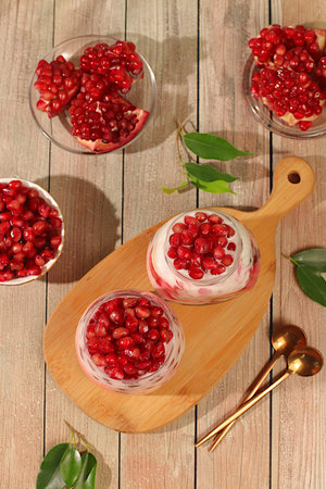 Fruit yogurt with pomegranate seeds and fresh cream for healthy nutrition in a glass on an elegant table. Healthy breakfast with ingredients, kitchen background.の写真素材