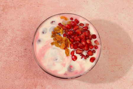 Bowl of pomegranate yogurt with pomegranate pieces, raisins and fresh cow cream for healthy eating...
