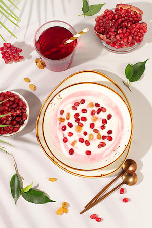 Healthy breakfast with ingredients. Pomegranate yogurt with pomegranate berries, raisins and juice on sunny table, fruit salad, natural nutrition concept, Healthy lifestyle advertising.の写真素材