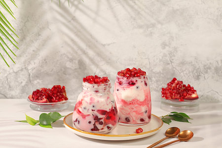 Modern still life with berries and drinks. Pomegranate yogurt with berries in a glass on an elegant...