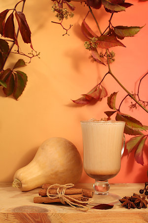 Warming pumpkin latte with cinnamon, star anise and fallen leaves, Seasonal abstract composition with hot autumn drink, banner for screen, autumn greeting concept, cafe menu mockupの写真素材