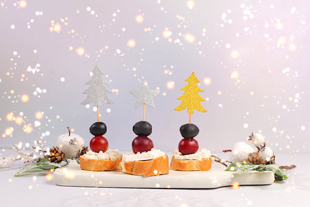 Christmas and New Year's dishes, a set of appetizers for the festive table. Canapes with soft cheese, grapes, and olives on a marble table, concept.の写真素材