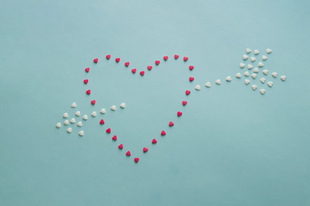 Blue background with small hearts making big one with arrow.の写真素材