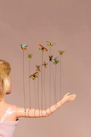 Butterflies on the soft dirty pink background taking hand. Dominating yellow wings  with lot of vivid colors.の写真素材
