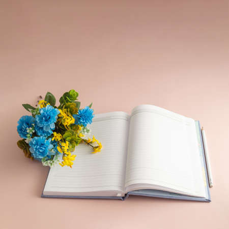 Notebook, pencil and spring flower on the pastel background. Minimalistic ideaの写真素材