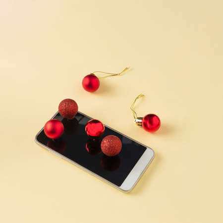 A phone with red Christmas balls on a yellow background.の写真素材