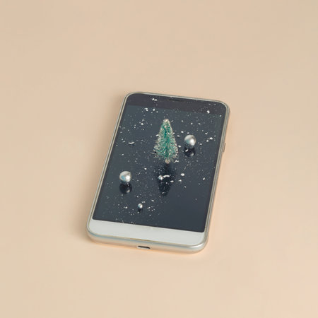 Cell Phone with Christmas tree, snow and shine balls on pink background.の写真素材